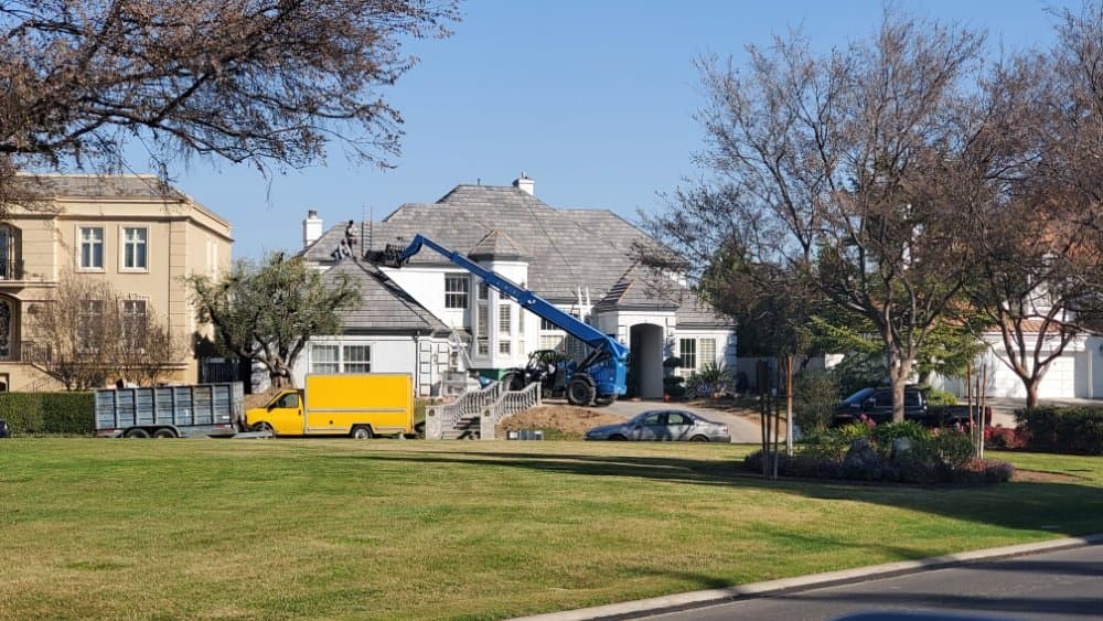 Crew replacing shingles on a large two-story home